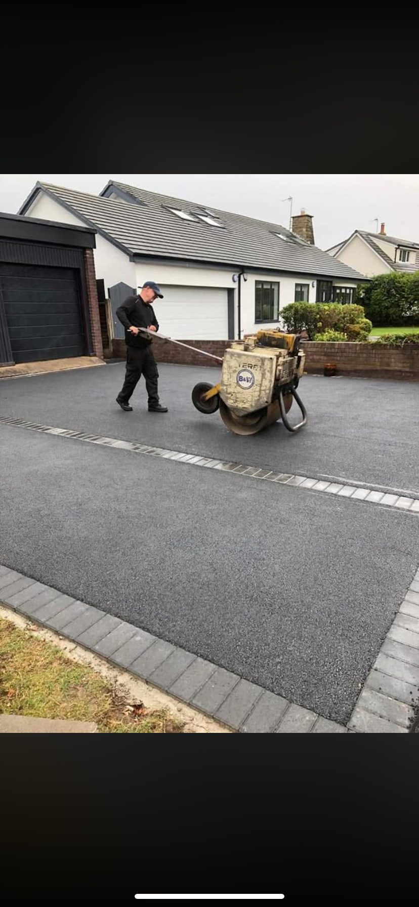 A member of the Hedgeway Paving team rolling a newly laid tarmac driveway